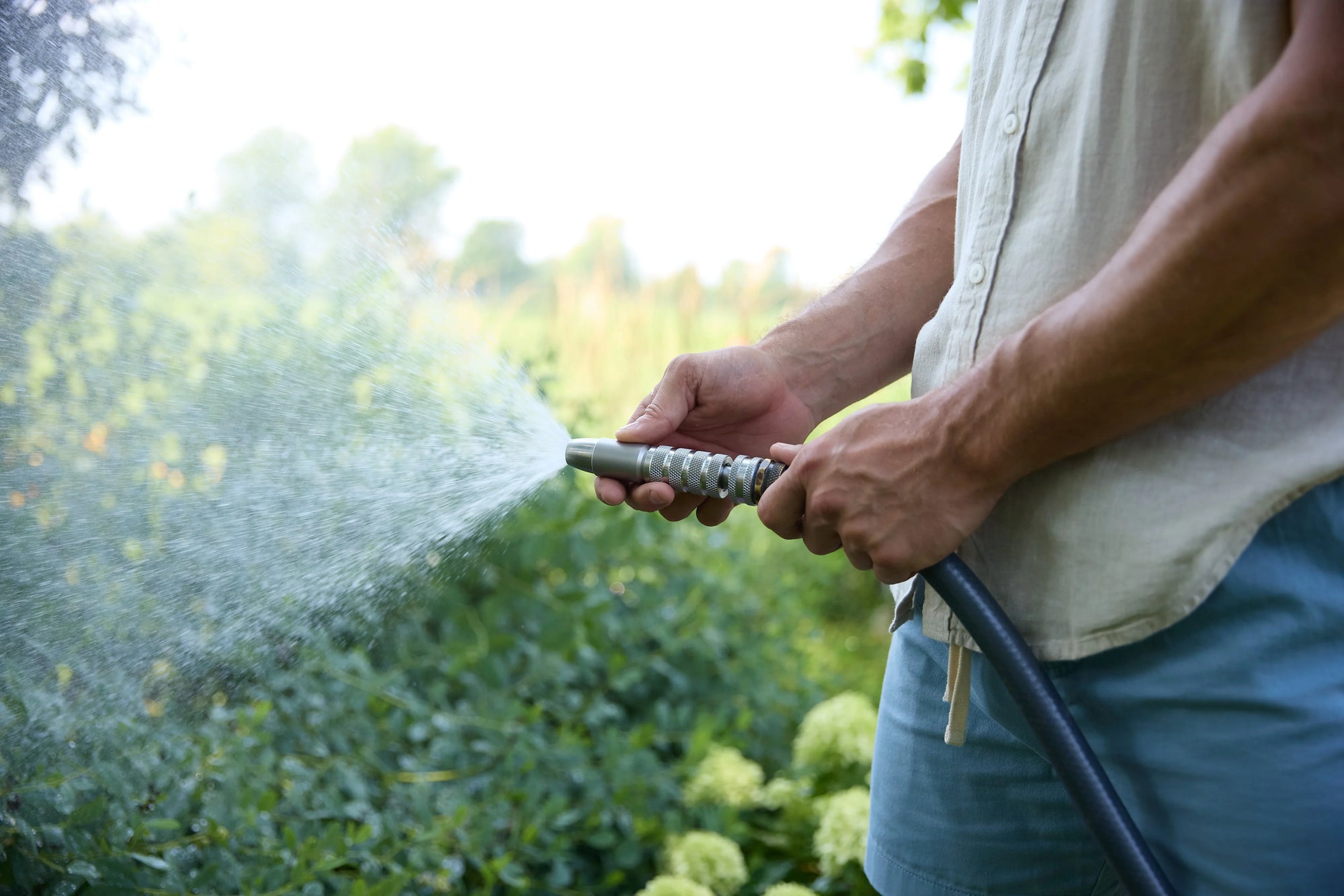 Stainless steel spray nozzle in use watering garden plants outdoors